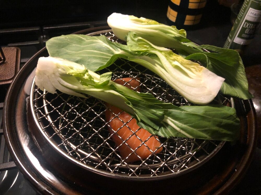 Photo of bok choy in double steamer on top of salmon